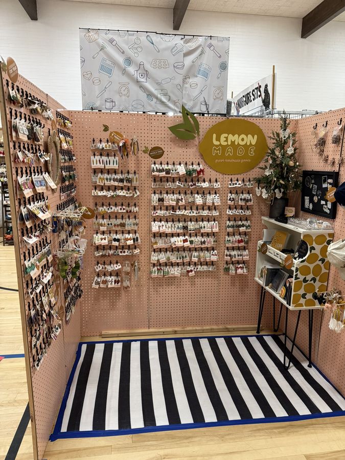 A styled vendor booth with a pink pegboard wall of earrings and a black and white striped rug