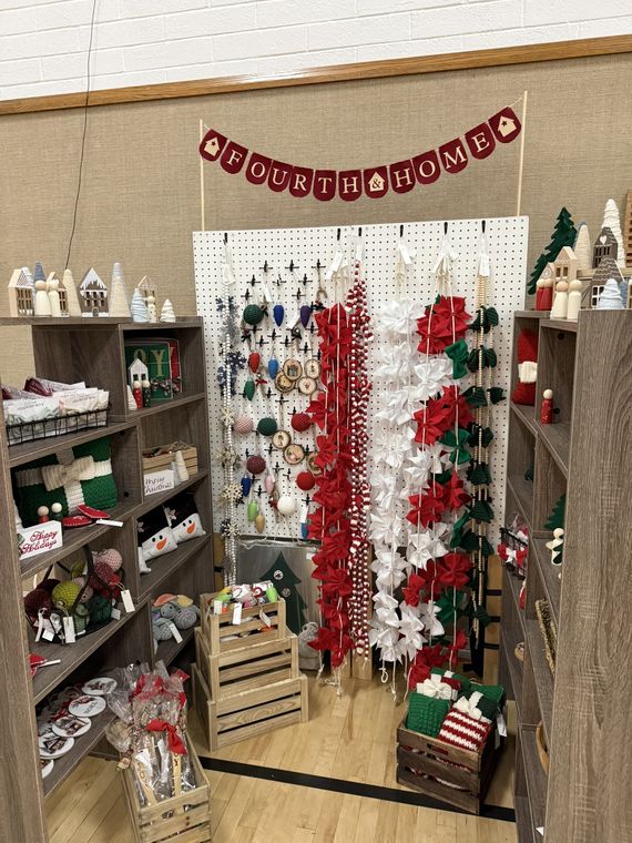 A red and white Christmas booth with wreaths, poinsettias, and holiday decor